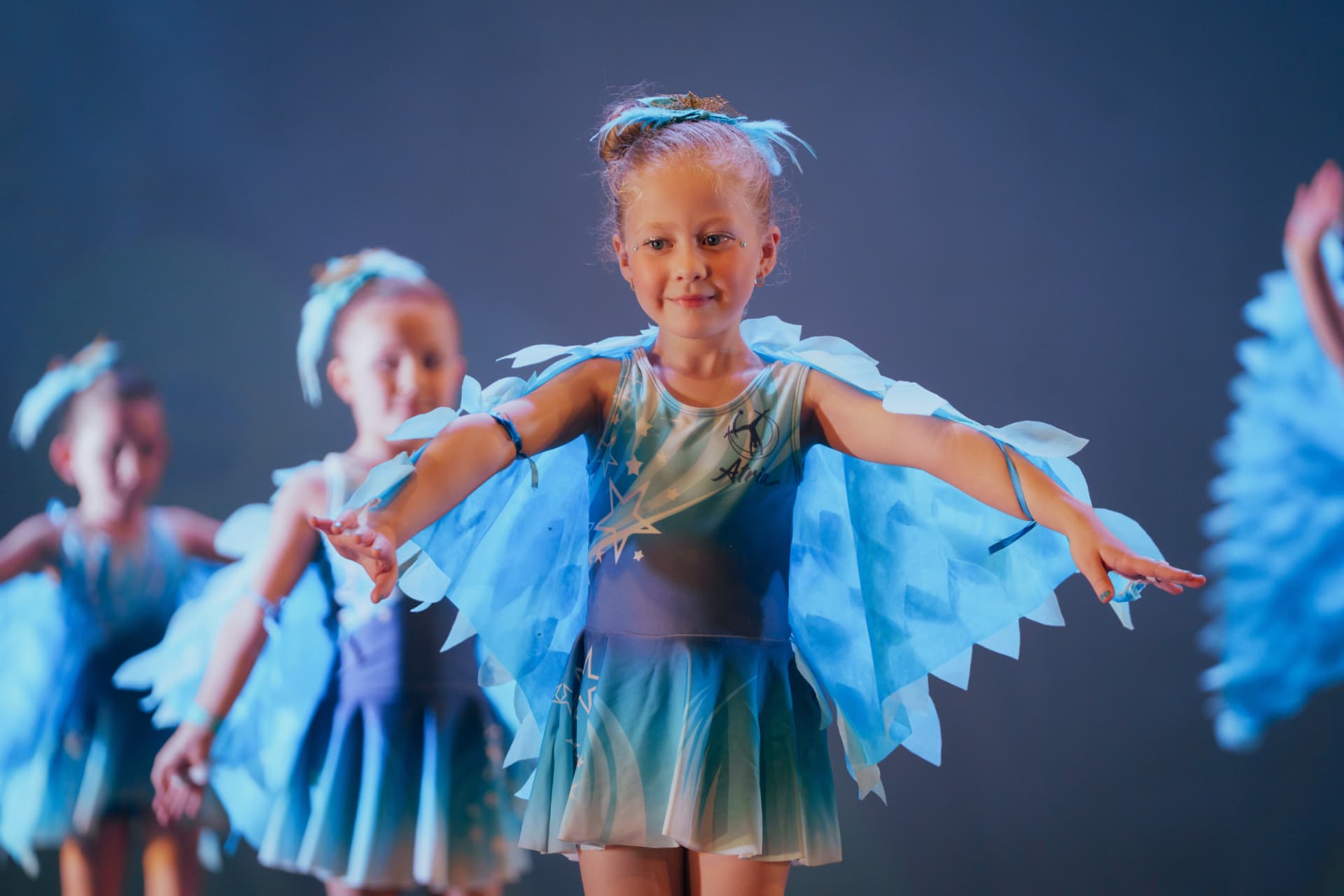 Bailarina sorrindo com figurino de asas azuis